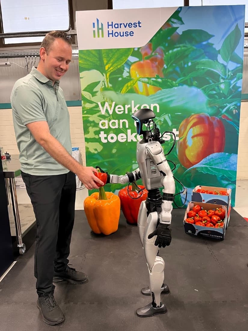 Harvest House employee handing a pepper to a humanoid at the Harvest House booth