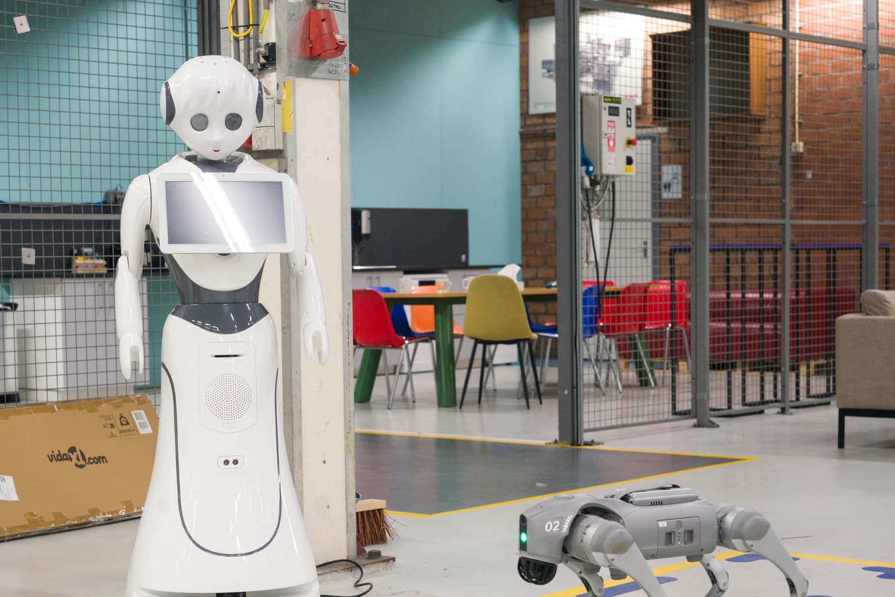 A service robot with a screen and a robot dog on the HAC shop floor